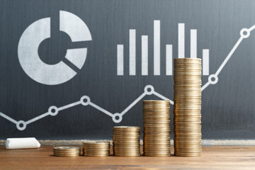 Portfolio investment. Strategy of asset management. Stack of coins and graphs drawn on blackboard.