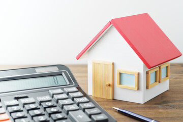 Miniature house and calculator on wood table. Concept image of value of home.