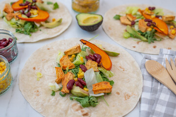 Open vegan tortilla wraps with sweet potato, beans, avocado and pumpkin