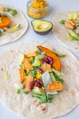 Open vegan tortilla wraps with sweet potato, beans, avocado and pumpkin