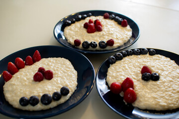 Oatmeal porridge with berries, in a blue plate. Healthy breakfast.