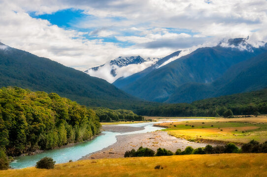 Amazing close-up view at Cameron Flat picturesque landscape in Mount Aspiring National Park, along Makarora River, with snow-capped mountain peaks in the background engulfed in clouds, in New Zealand.