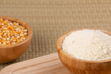 Wooden bowl of cornmeal or cornflower on a wooden background