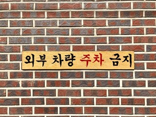 A sign in front of a brick wall