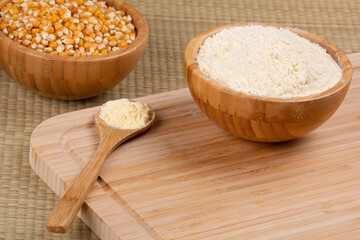 Wooden bowl of cornmeal or cornflower on a wooden background