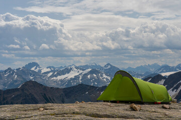Green tent in remote campground in Bugaboos national park in British Columbia, Canada during hot summer month with amazing views on surrounding mountains