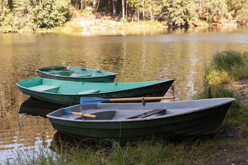 Three small rowboats are moored at coast