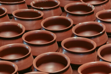 Row of unbaked clay terra cotta pots at traditional pottery shop near Gujarat, India. Top view large and short ancient flower pots. Raw baked clay earthenware full frame background