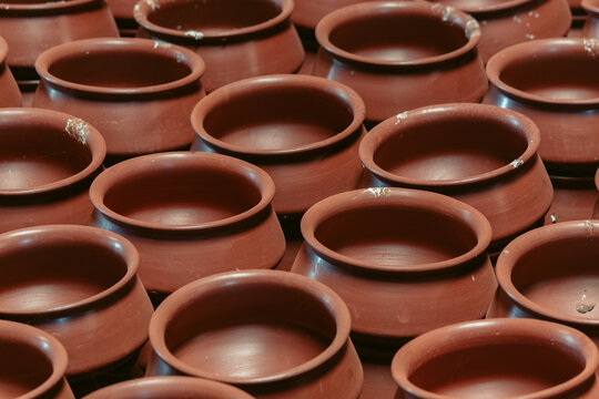Row of unbaked clay terra cotta pots at traditional pottery shop near Gujarat, India. Top view large and short ancient flower pots. Raw baked clay earthenware full frame background