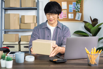 Asian business man startup SME entrepreneur or freelance working in a cardboard box prepares delivery box for customer, Online selling, e-commerce, packaging and shipping concept.