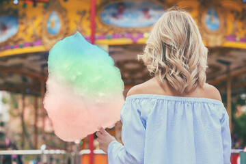 Woman holding colorful cotton candy outdoors,  back view