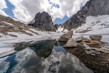 Reflection in glacier lake of snow, cloudy sky and Bugaboo spire in Bugaboos provincial park, British Columbia, Canada in landscape