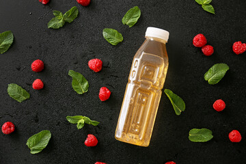 Bottle of fresh ice tea, mint and raspberry on dark background