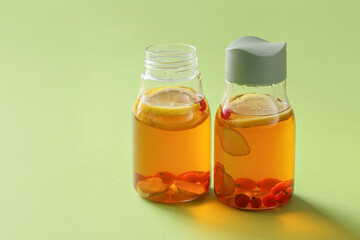 Bottles of fresh ice tea on color background