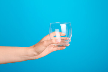 Hand with empty glass on color background