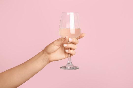 Hand with glass of wine on color background