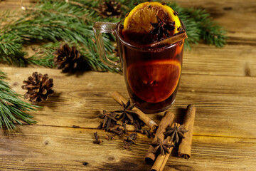 Christmas mulled wine with spices and fir tree branches and cones on wooden table