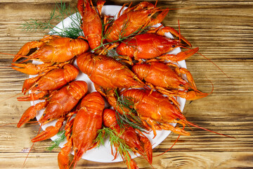 Boiled crayfish in plate on wooden table. Top view