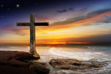 Crucifix crucifixion Jesus Christ on the rocks by the sea at sunset.
