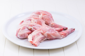 Raw rabbit legs on white plate