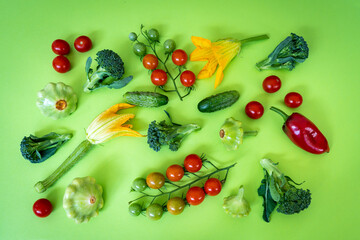Various fresh colorful organic vegetables captured from above on green background.  Ingredients for cooking - tomato , cucumbers, broccoli, red pepper and squash flat lay