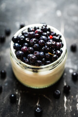Freshly harvested bilberries with plain greek yogurt in the jar. Selective focus. Shallow depth of field.