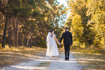 happy bride and groom are walking in the green park