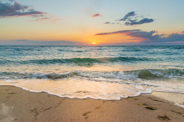 White foam waves on the sand at sunset in the sea