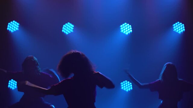 Three adorable girls are actively dancing jazz funk in the spotlight. Silhouettes of dancers close up.