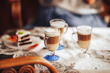 Glass mugs with delicious coffee on the table, sweet pastries, coffee break, family gatherings.