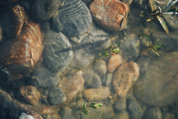 Background of river stones of different sizes in muddy water.