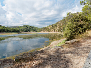 Fototapeta na wymiar Nice out-and-back walk twisting along Carcès lake or lake of sainte Suzanne lined with trees and wildflower when the water level is low during dry period