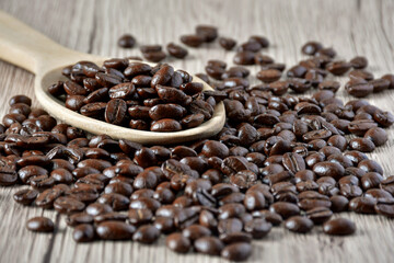 Close up Coffee beans in a wooden spoon on a table.