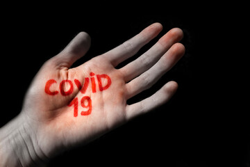 a young guy has covid-19 written on his palm.  transmission of the covid-19 virus through a handshake, selective focus.