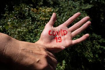 a woman holds a man's hand on which is written covid-19. living with coronavirus and interacting with people with coronavirus.