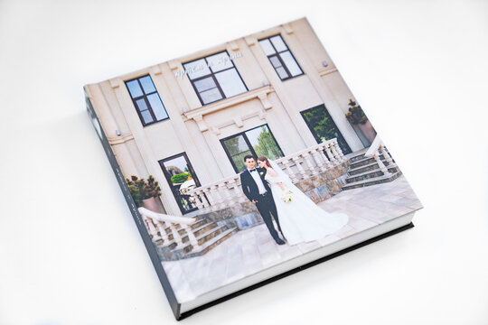 wedding photobook with thick pages on a white table. convenient, beautiful and long-lasting storage of photos from photo sessions. Russian names Artyom and Arina are written on the cover.