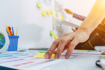 The team of website designers with the ux ui system are writing programs and laying the layer to determine the display style with the ux ui system within the front of the smartphone.