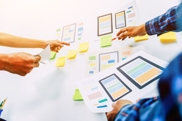 The team of website designers with the ux ui system are writing programs and laying the layer to determine the display style with the ux ui system within the front of the smartphone.