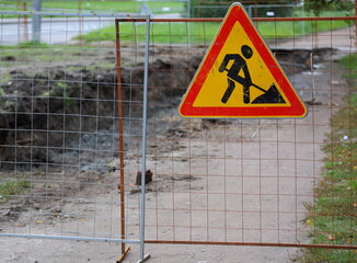 A moat enclosed by a lattice fence with signs of earthworks for laying underground communications