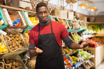 Obraz premium Portrait of successful African American salesman inviting to fruit and vegetable store, offering fresh products..