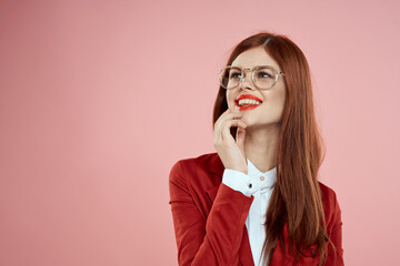woman in red jacket with glasses red lips long hair pink background