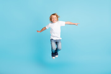 Photo of small child jump raise hands legs wear white shirt jeans sneakers isolated blue color background