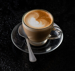 a cappuchino glass with a spoon, black background