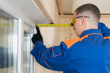 master in blue special clothes measures the thickness of the wall with a tape measure