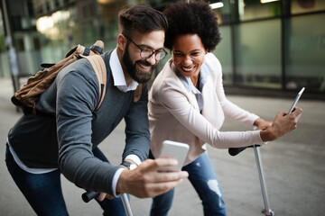 Happy businesspeople using technology devices gadgets near wall of modern building