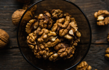 Walnut in a smale plate with scattered shelled nuts and whole nut which standing on a wooden vintage table. Walnuts is a healthy vegetarian protein nutritious food. Walnut on rustic old wood.