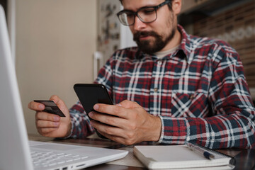 Handsome man using credit card to pay online with smartphone