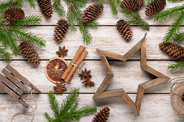 Spruce branches and cones on light wooden background, accessories for winter holidays. Christmas card, congratulations.