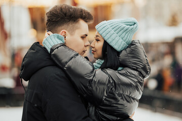 Close up of couple in the winter. Young couple on winter holidays. Handsome young man embracing his girlfriend. Loving couple in warm clothing outdoors. 