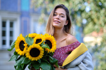 Young fashion  woman with a bouquet of sunflowers in the city